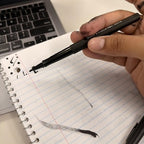Ejemplo de uso de un marcador Paper Mate Flair negro escribiendo sobre un cuaderno.