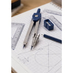 Ejemplo ilustrativo de uso: trazado de figuras geométricas con compás e instrumentos de dibujo. Escena generada por IA; no fotografía oficial ni inventario del contenido del kit Faber-Castell S67007. Papel y elementos de ambientación no incluidos.